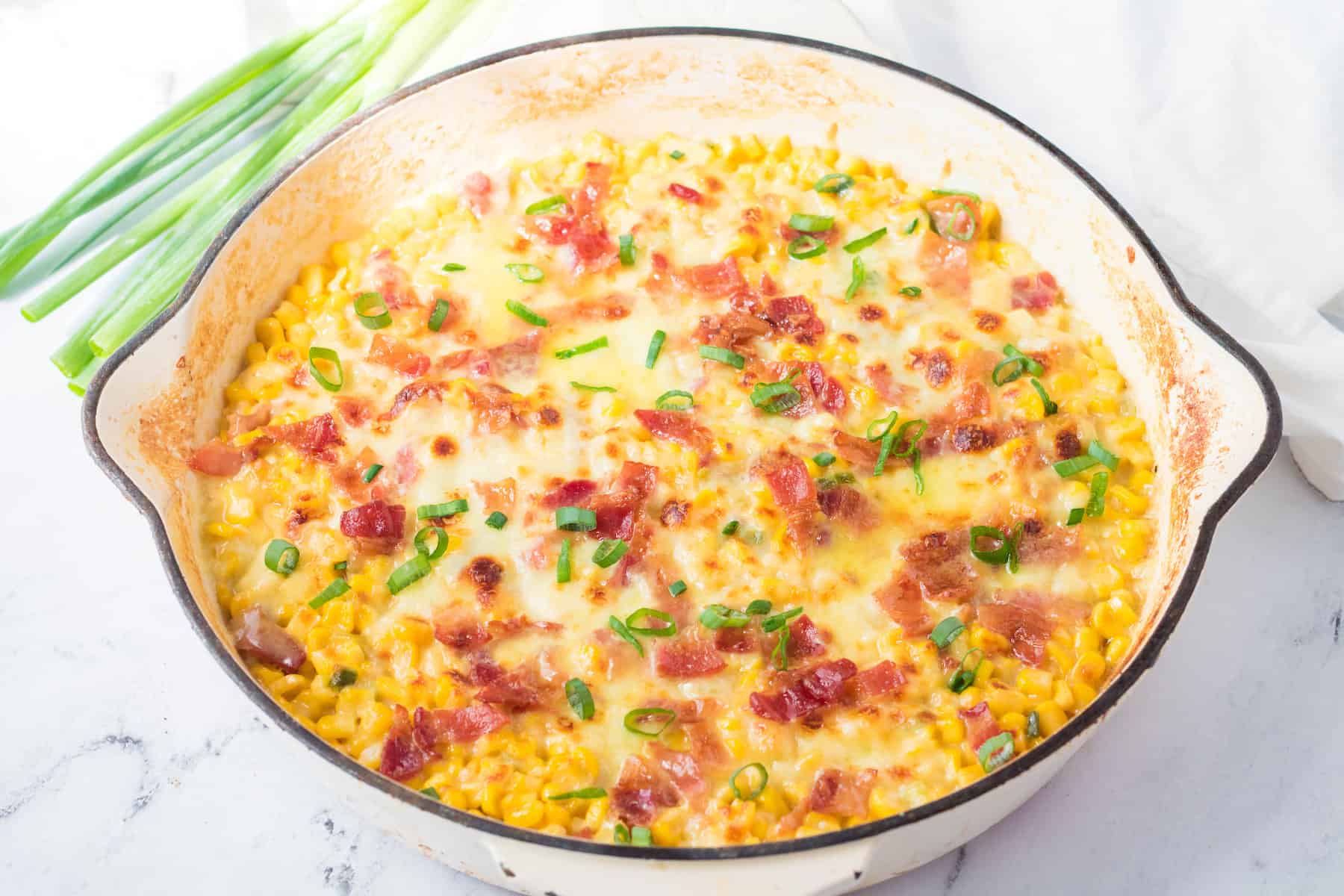 cheesy skillet corn with bacon and green onions in a skillet