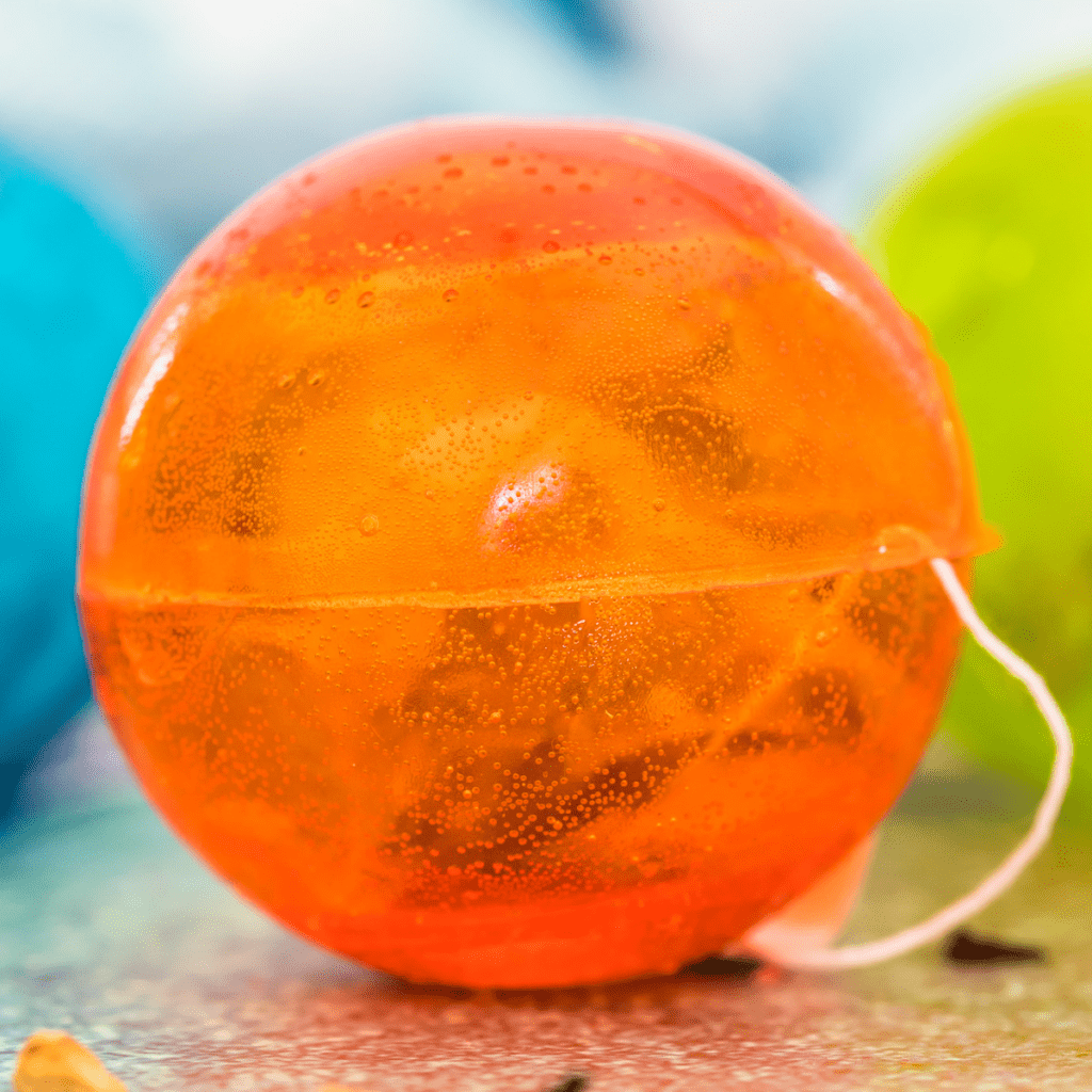 an orange hot tea bomb with a tea bag string sticking out