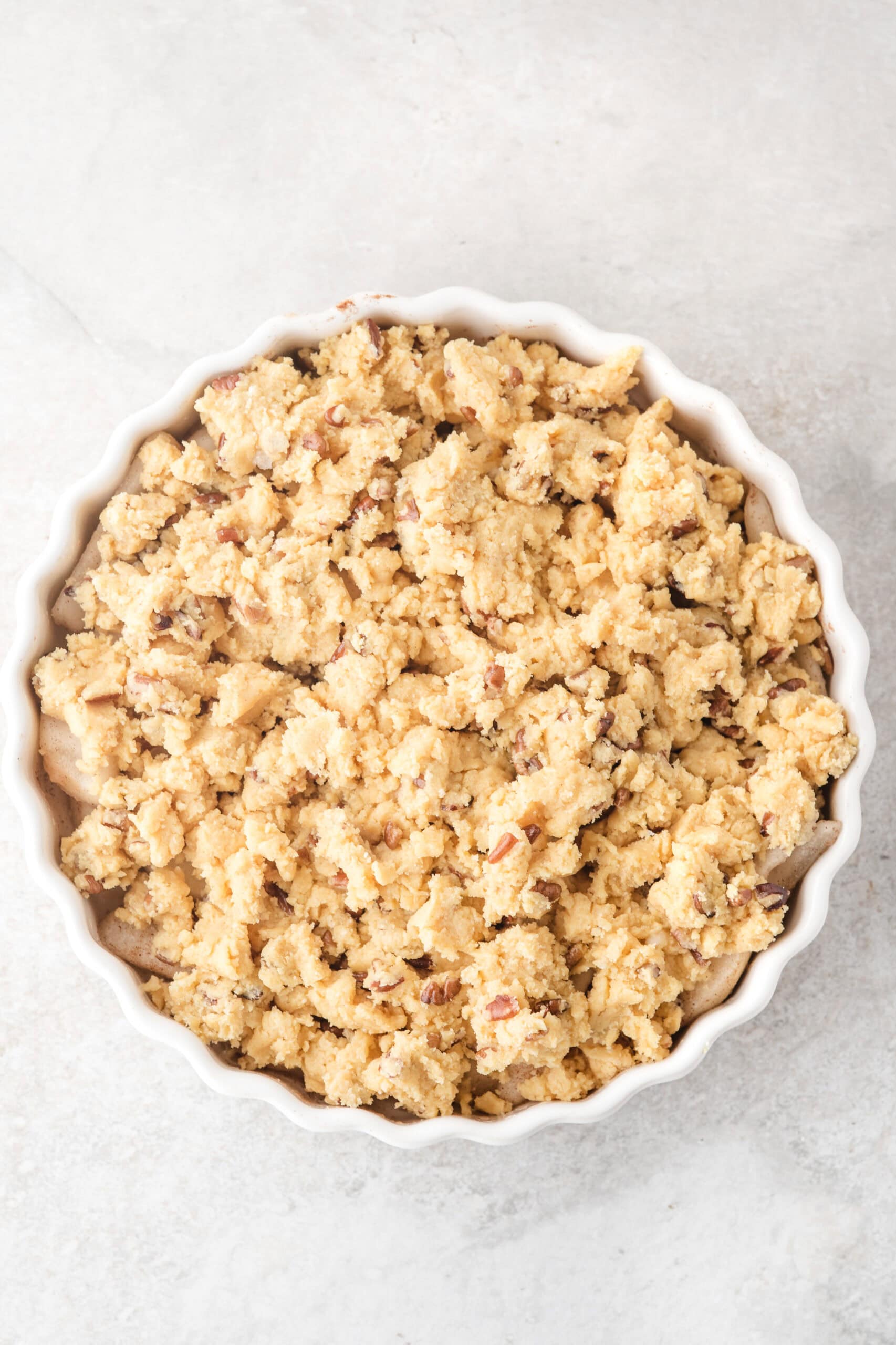 Fresh pears arranged in pan, cake mixture with melted butter and nuts are put together and all sprinkled evenly across pears to be baked