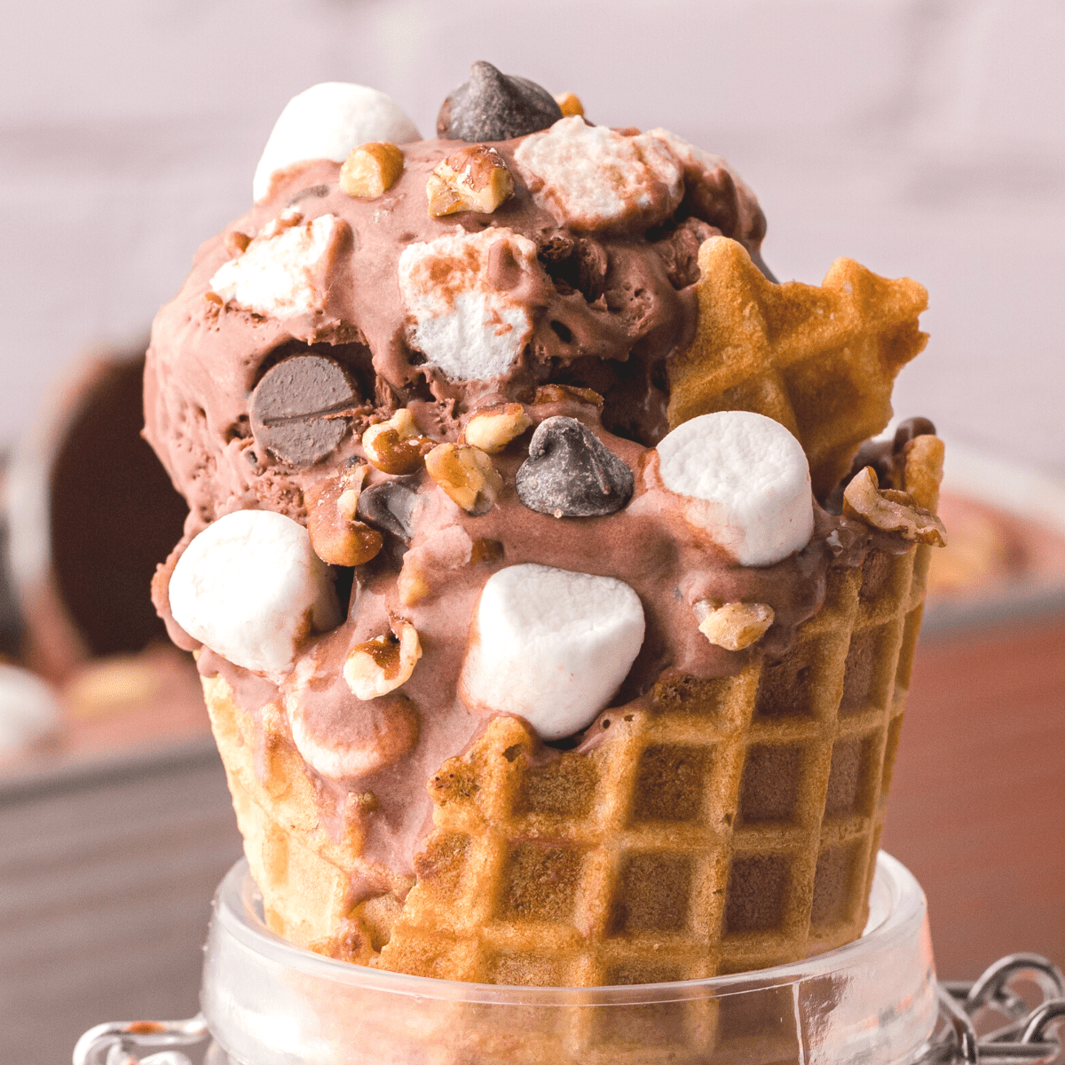 An ice cream cone containing homemade rocky road ice cream with marshmallows, pecans, and chocolate chips