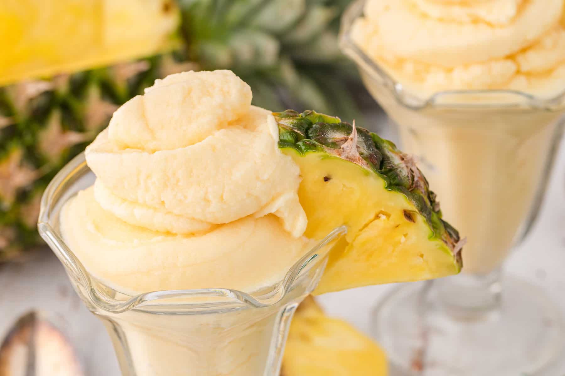 a dish of homemade pineapple ice cream with a chunk of fresh pineapple