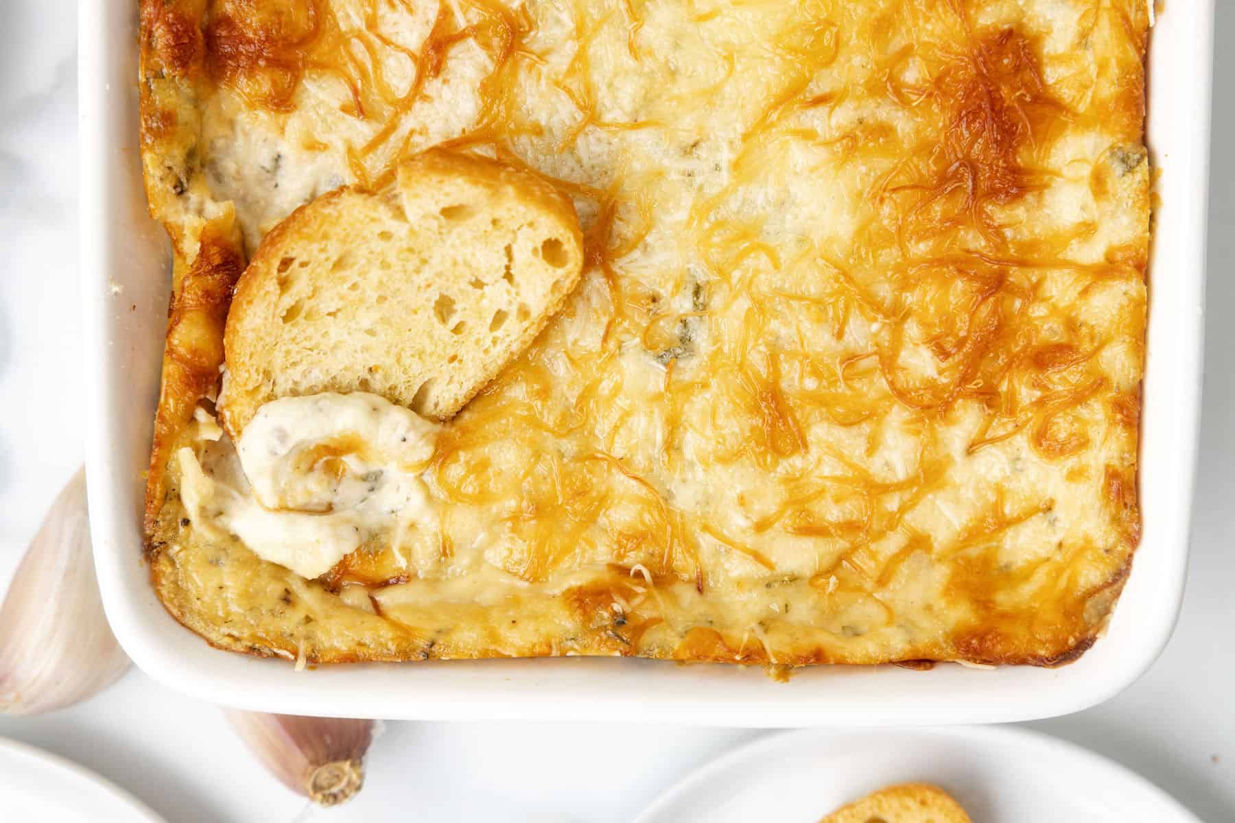 a crostini with the best cheesy garlic dip recipe spread on it
