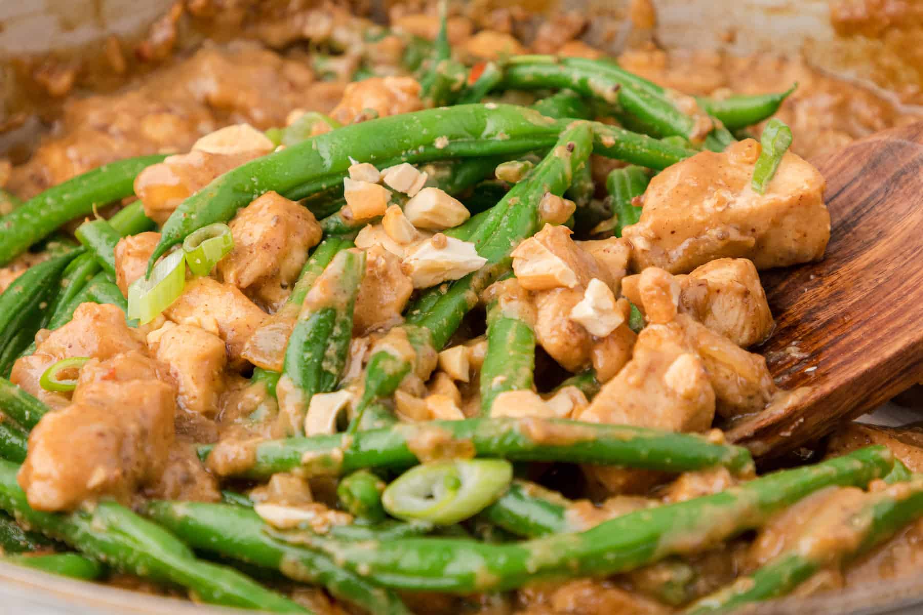 a close up of Indonesian peanut butter chicken with green beans in a skillet