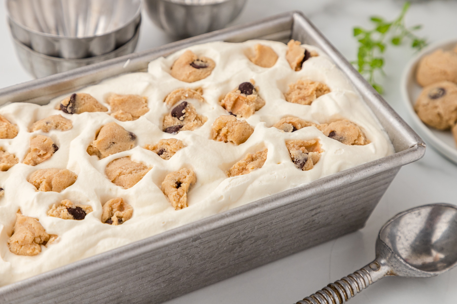 no churn cookie dough ice cream in a metal loaf pan with an ice cream scoop