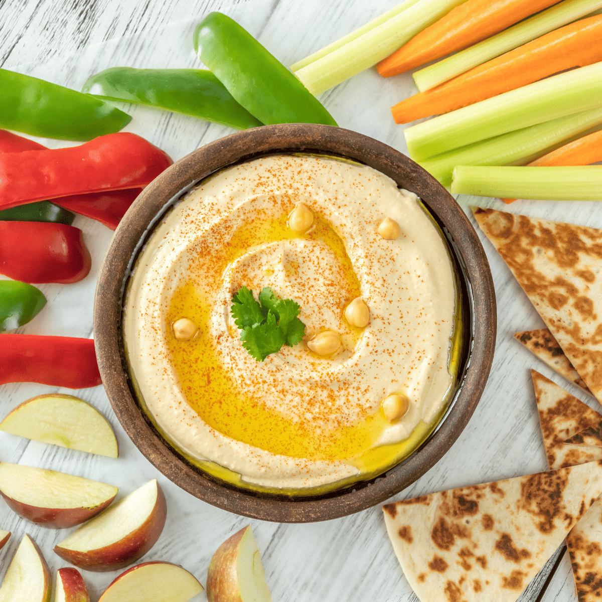 healthy homemade hummus surrounded by veggies and pita bread