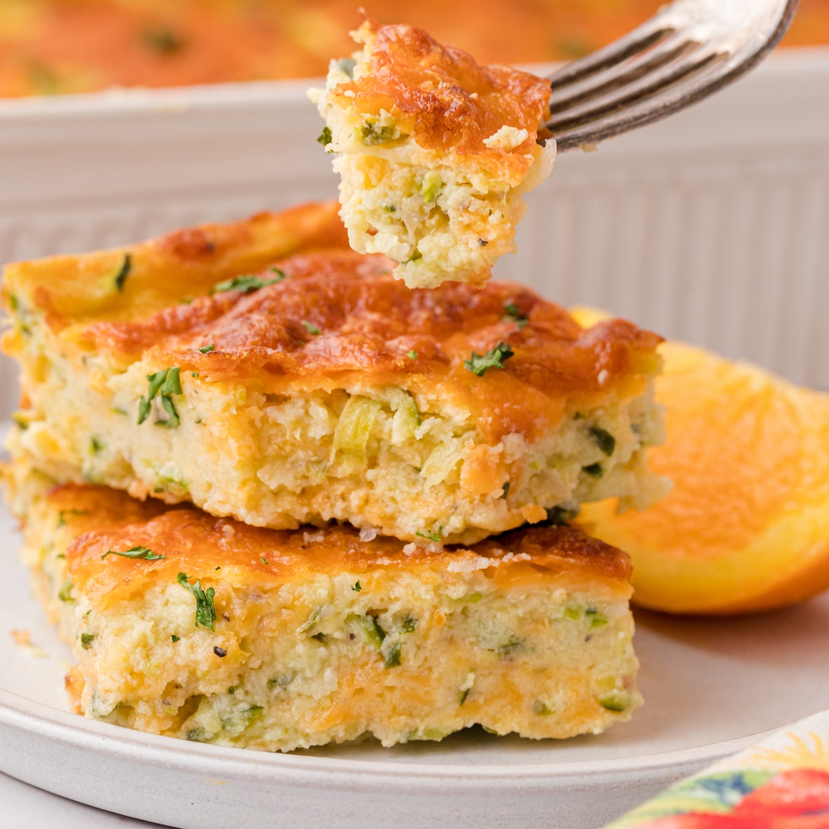 two squares of cheesy zucchini bake stacked on a white plate