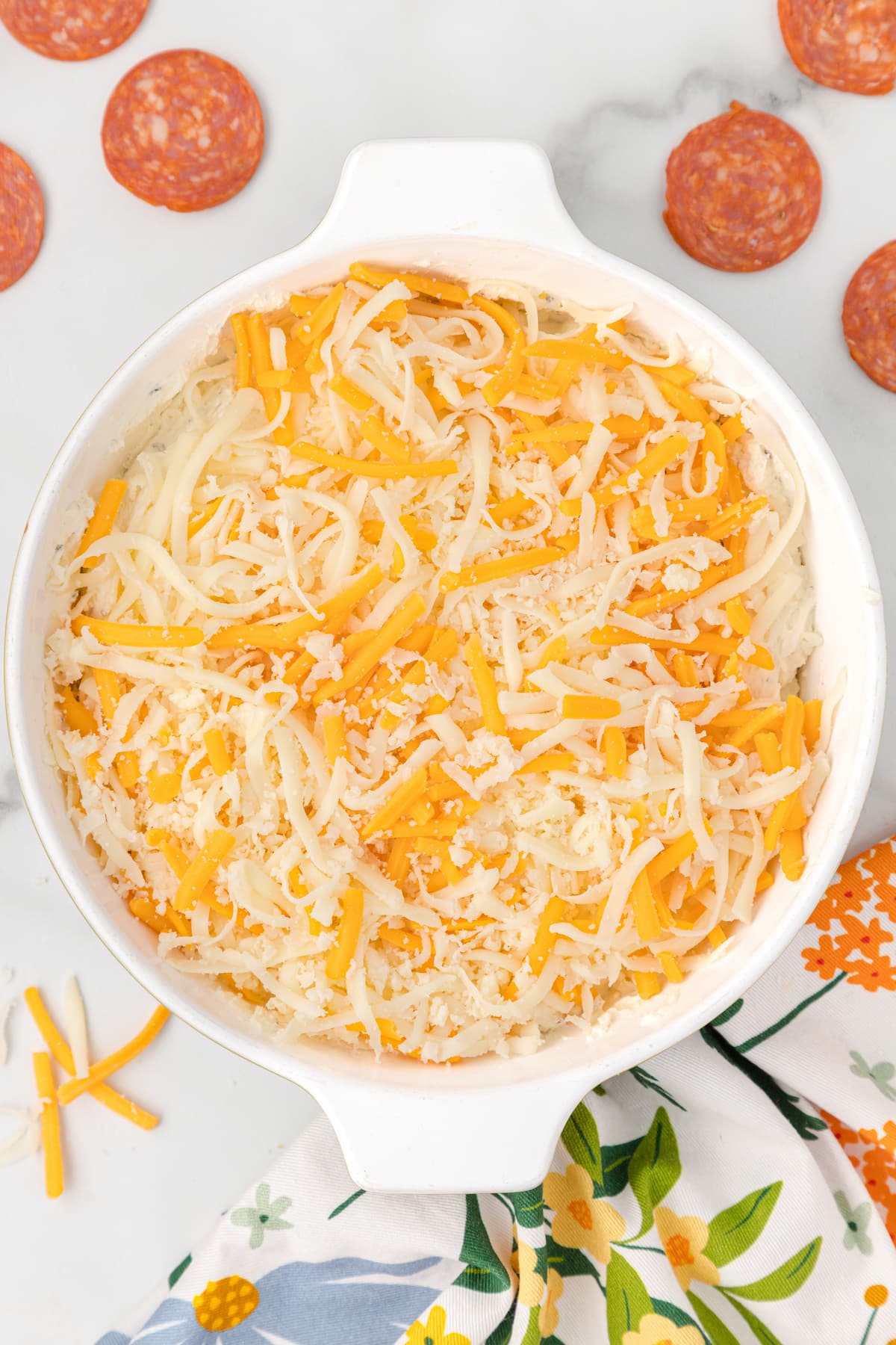 top the cream cheese mixture with shredded mozzarella and cheddar cheeses