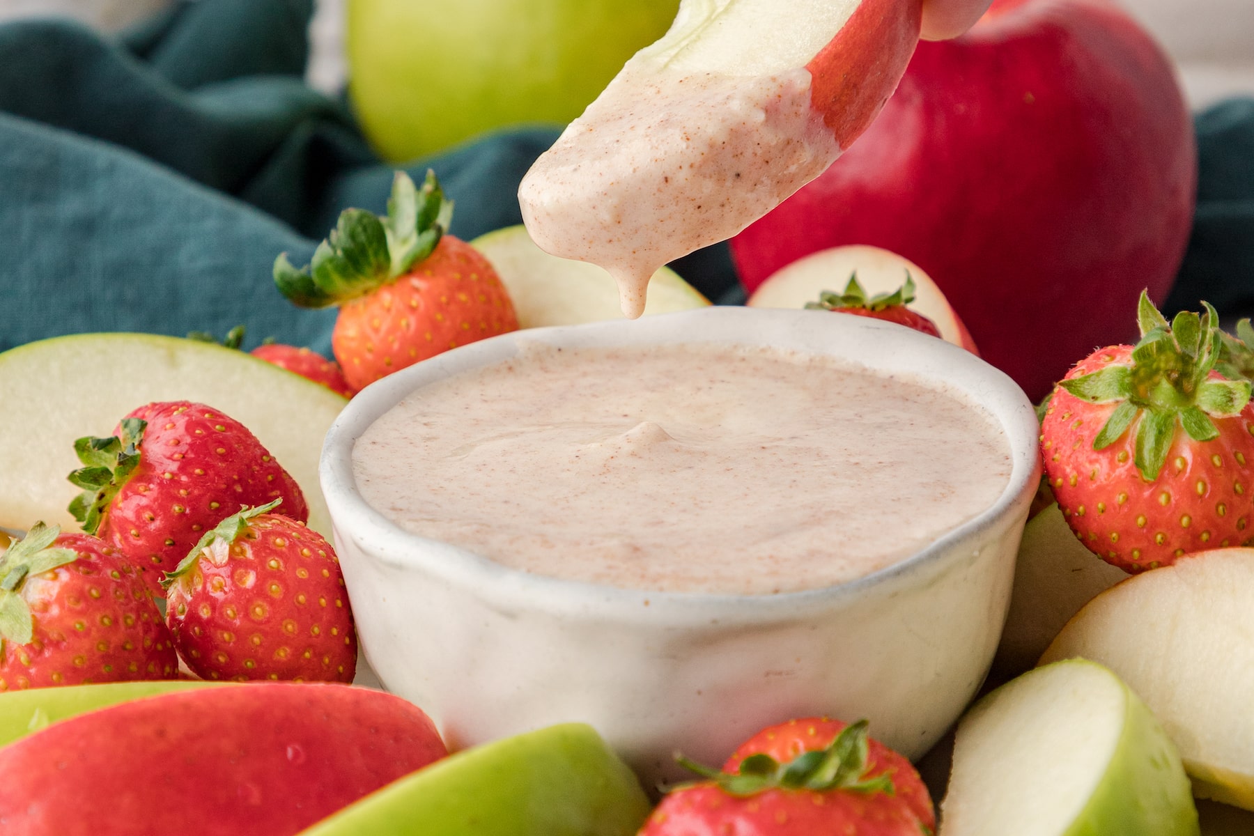 an apple dipped in cream cheese fruit dip with cinnamon