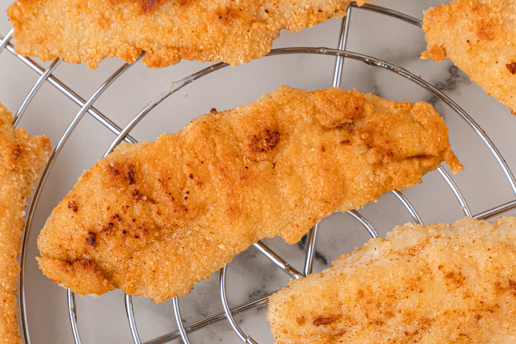 a close up of a gluten free chicken tender on a cooling rack