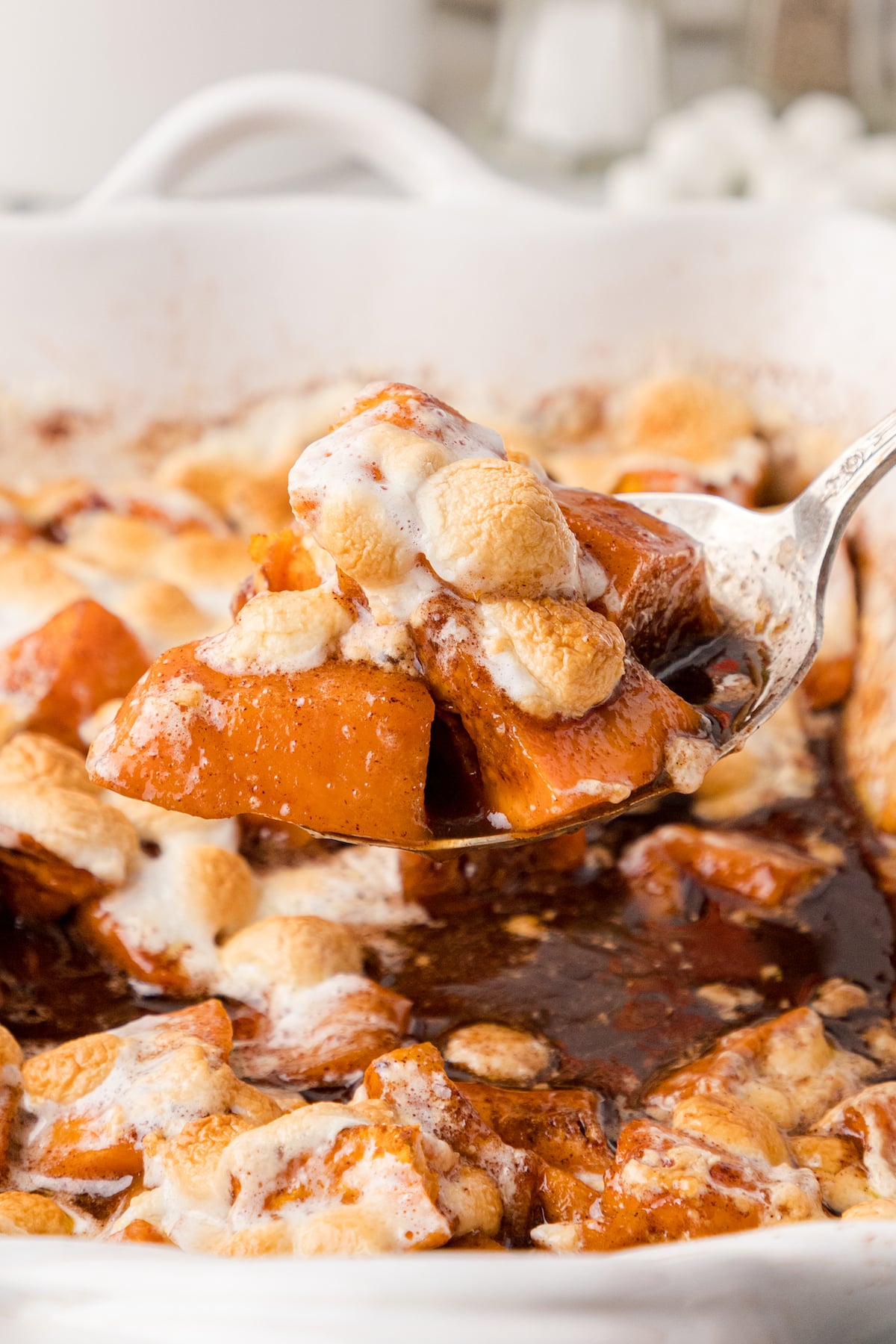 a close up of one serving of candied yams with marshmallows over top of the baking dish