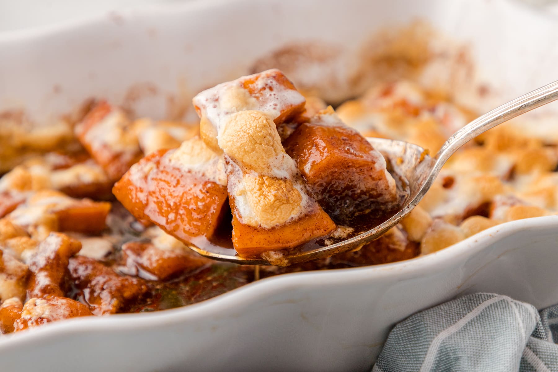 a close up of one serving of candied yams with marshmallows over top of the baking dish