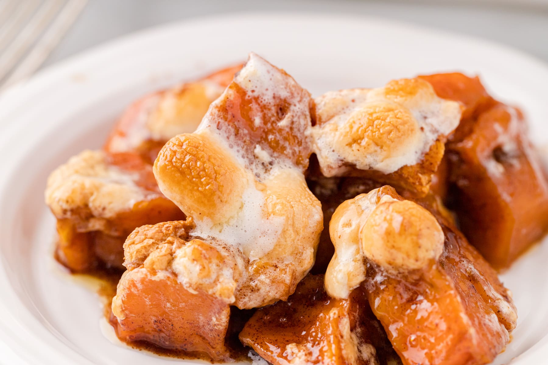 a close up of one serving of candied yams with marshmallows on a white plate