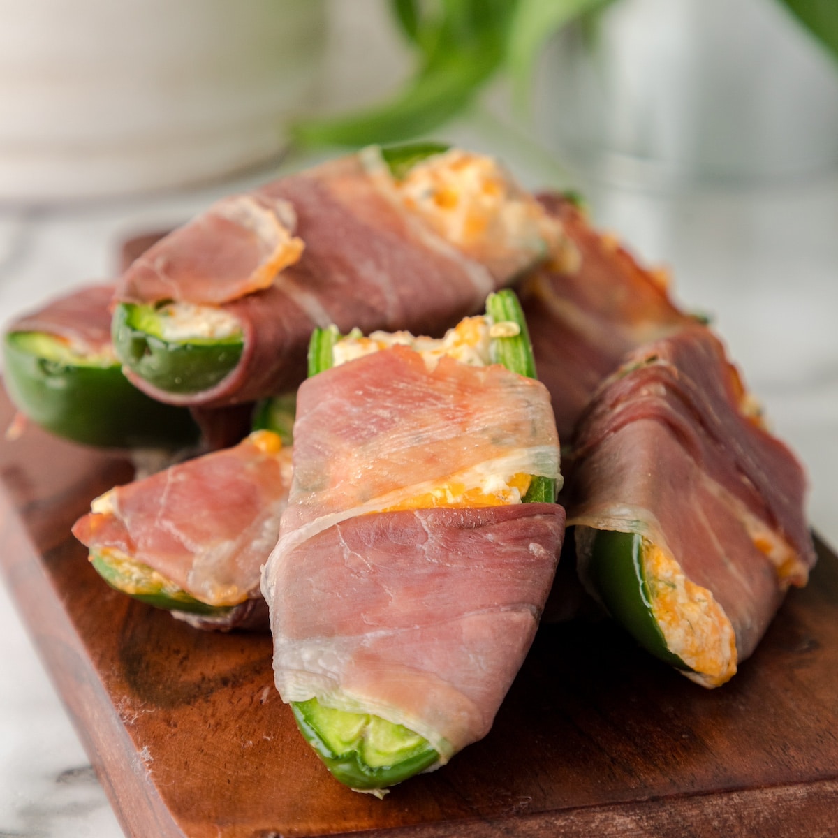 a stack of Prosciutto-Wrapped Jalapeño Poppers on a cutting board