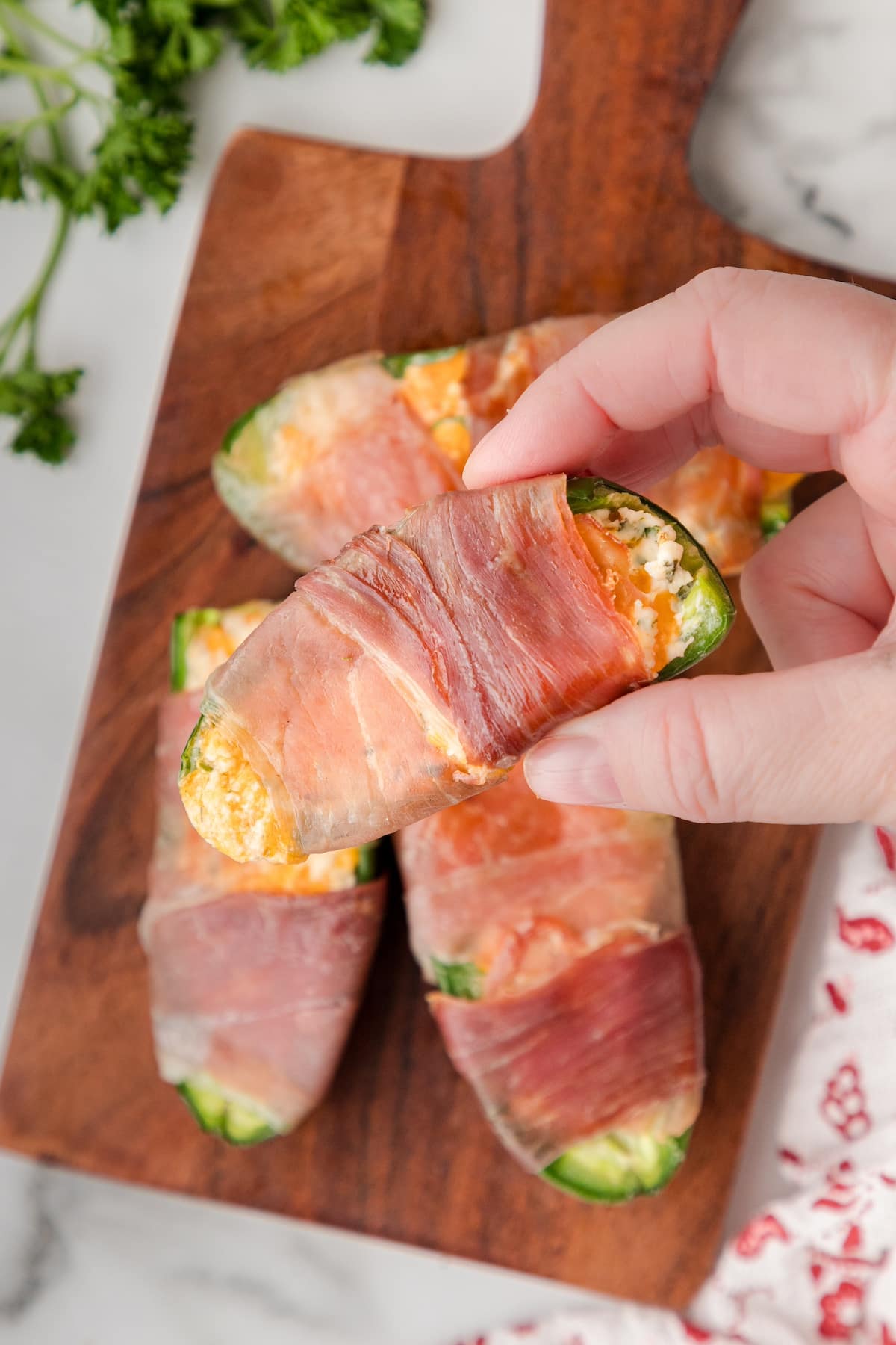 one keto jalapeno popper wrapped in prosciutto held in a hand