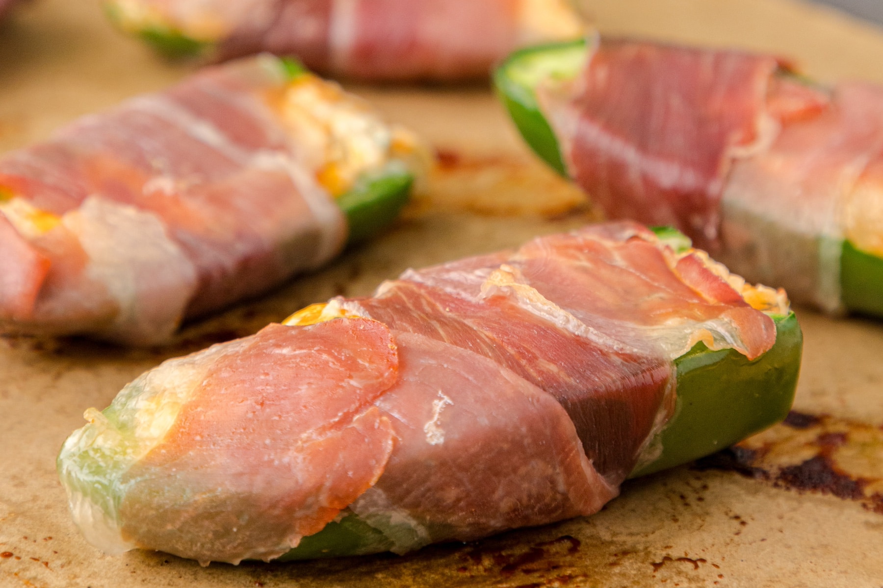 baked Low carb Keto Jalapeño Poppers with prosciutto on parchment paper