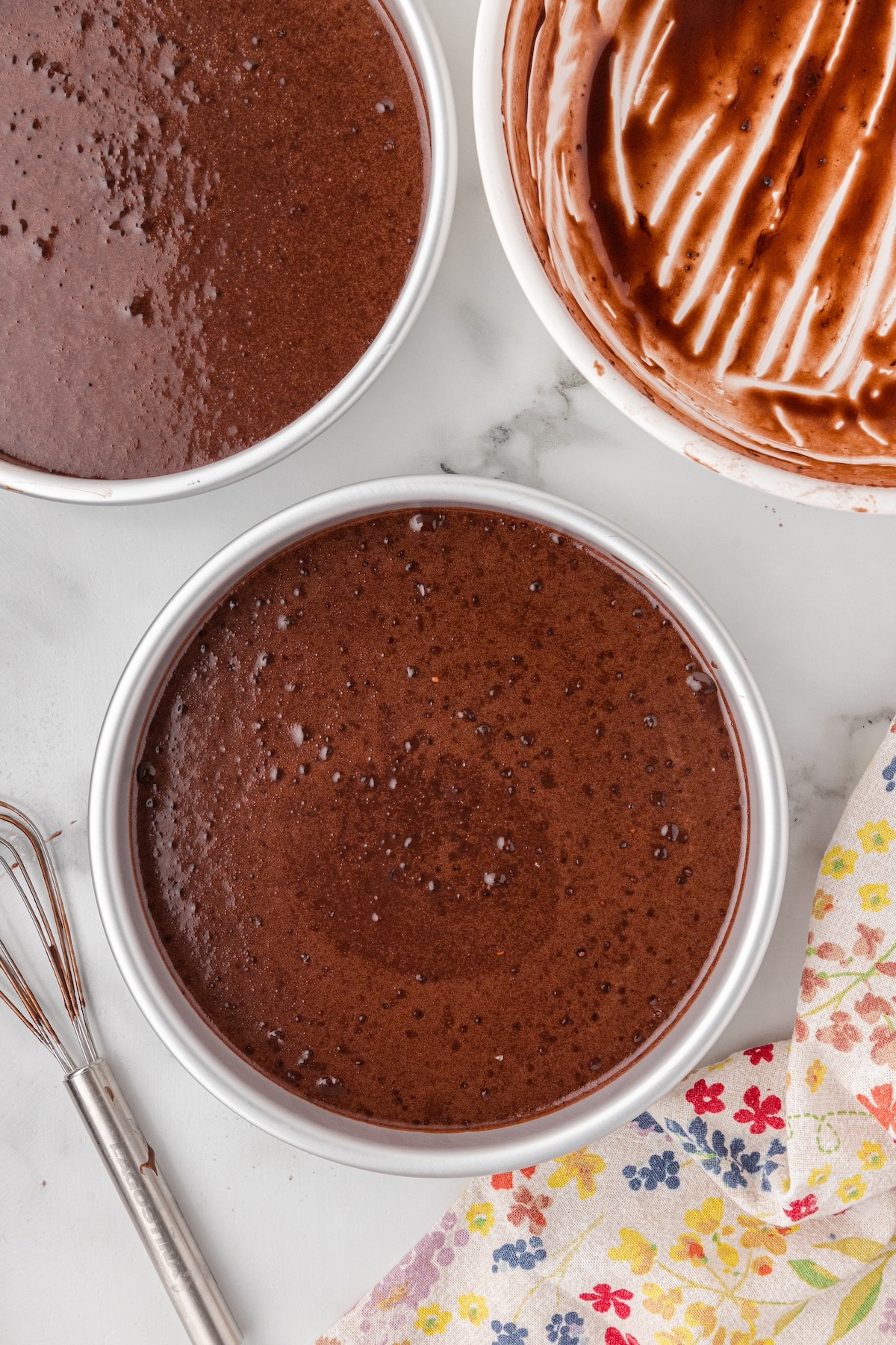 chocolate cake batter poured into prepared cake pans