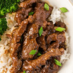 a close up of instant pot mongolian beef over rice topped with green onions
