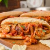 Italian sausage sandwiches on a cutting board with potato chips