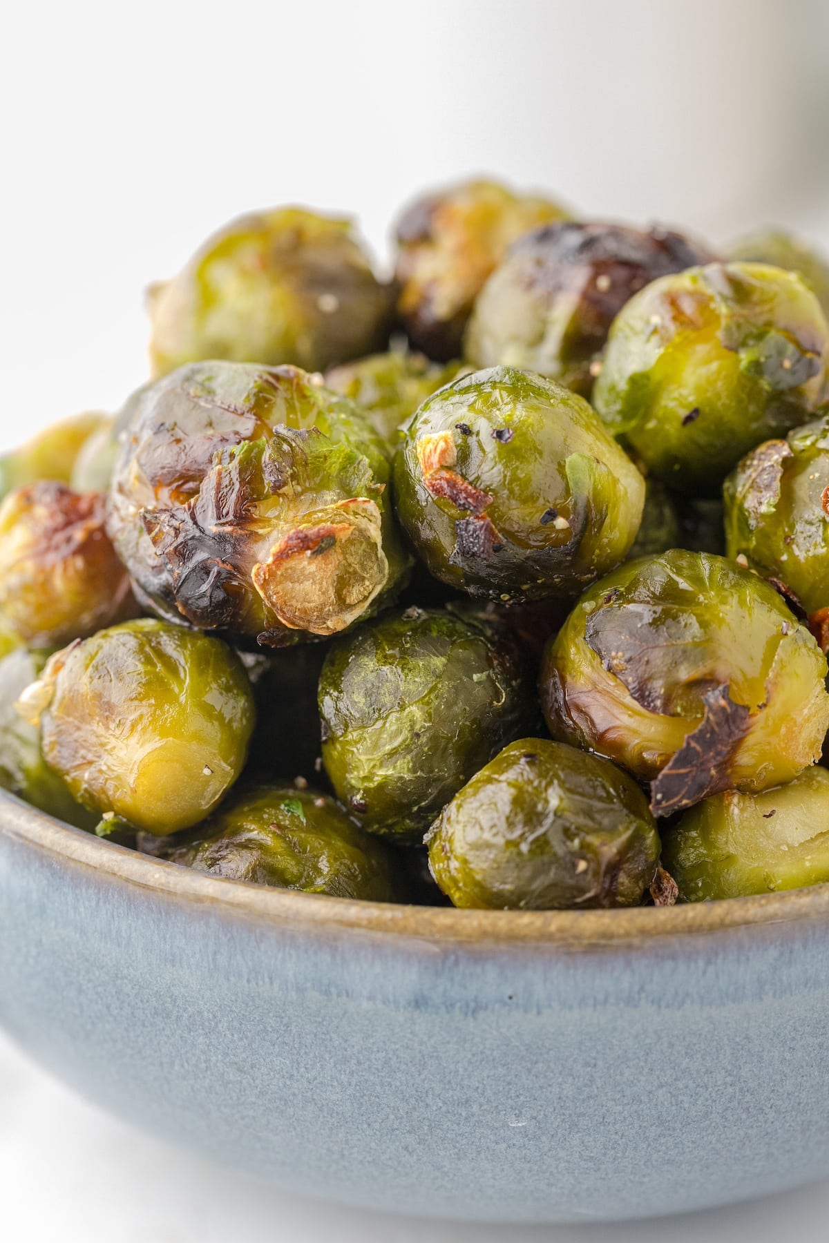 a close up of whole roasted brussels sprouts in a blue bowl