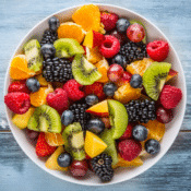 a bowl of fruit salad including kiwi, berries, oranges, and other fruits