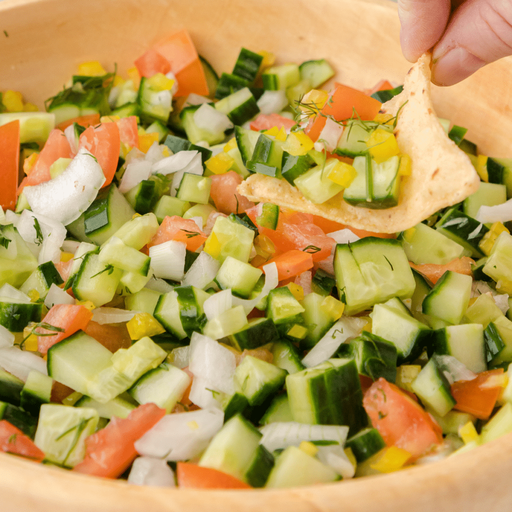cucumber salsa in a wooden bowl with a tortilla chip