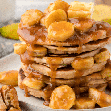 a stack of pancakes topped with bananas foster sauce and butter