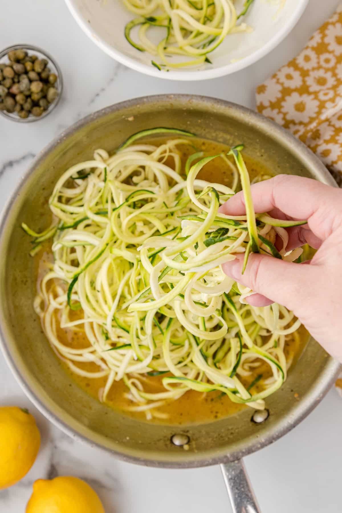 add the zucchini noodles to the piccata sauce in the skillet