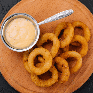homemade Burger King's Zesty Sauce with onion rings on a wooden platter