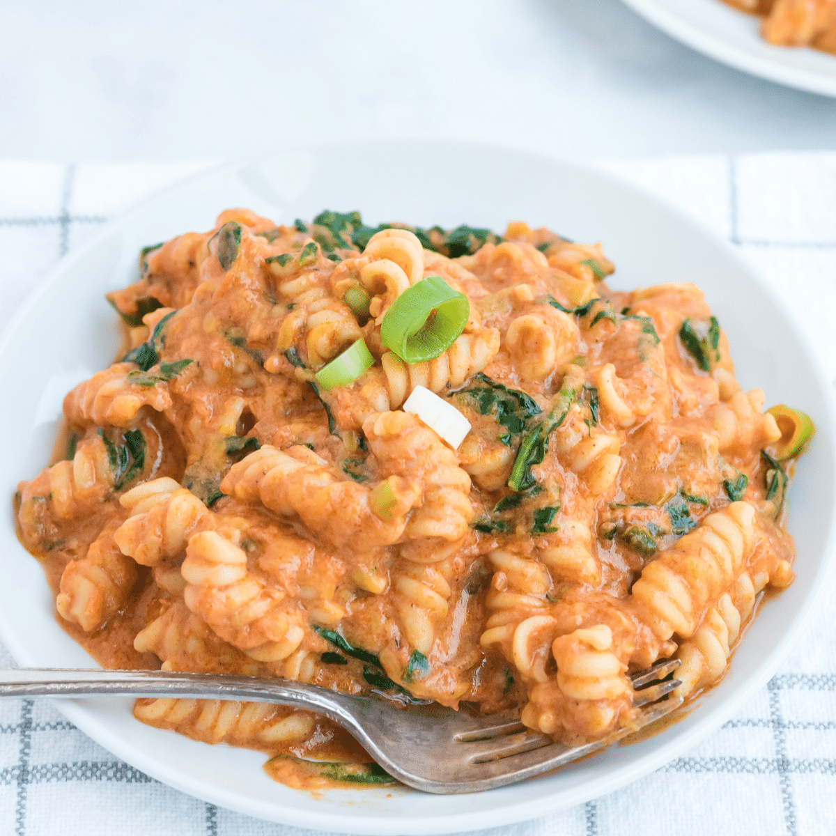 a plate of pasta with spinach and creamy red sauce