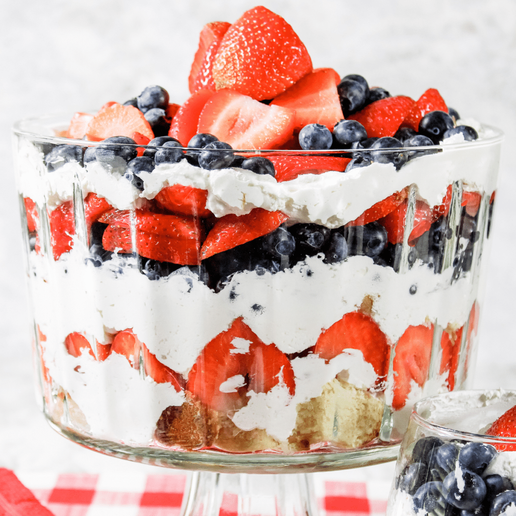 red, white, and blue berry trifle with cream cheese filling in a glass bowl