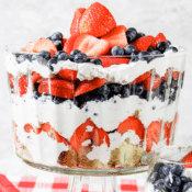 red, white, and blue berry trifle with cream cheese filling in a glass bowl