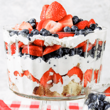 red, white, and blue berry trifle with cream cheese filling in a glass bowl