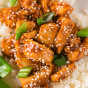 Healthy General Tso's chicken sprinkled with sesame seeds and green onions, over a bed of rice