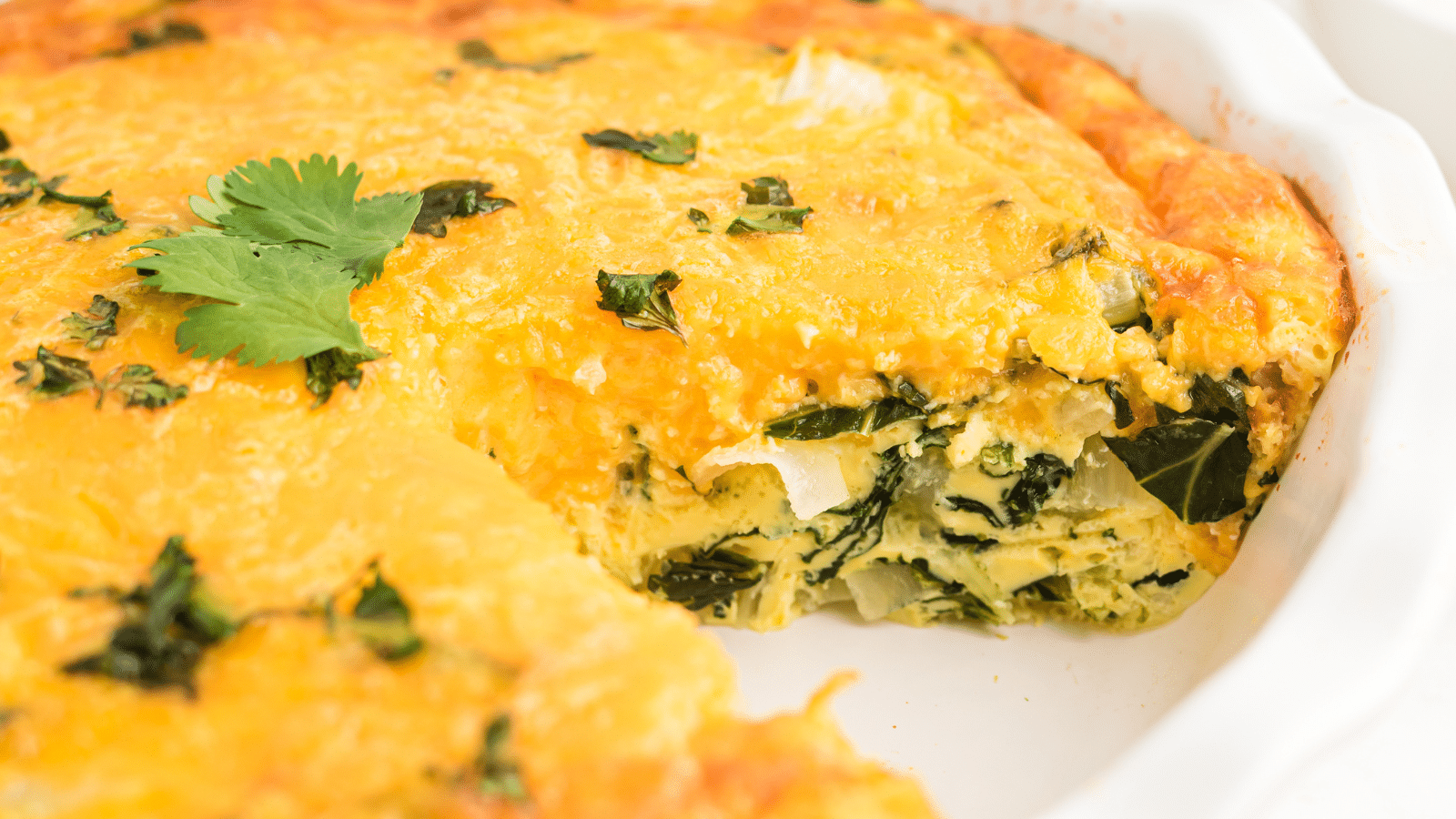 an oven baked veggie omelet with one slice removed, viewed from the side to show the veggies mixed into the egg