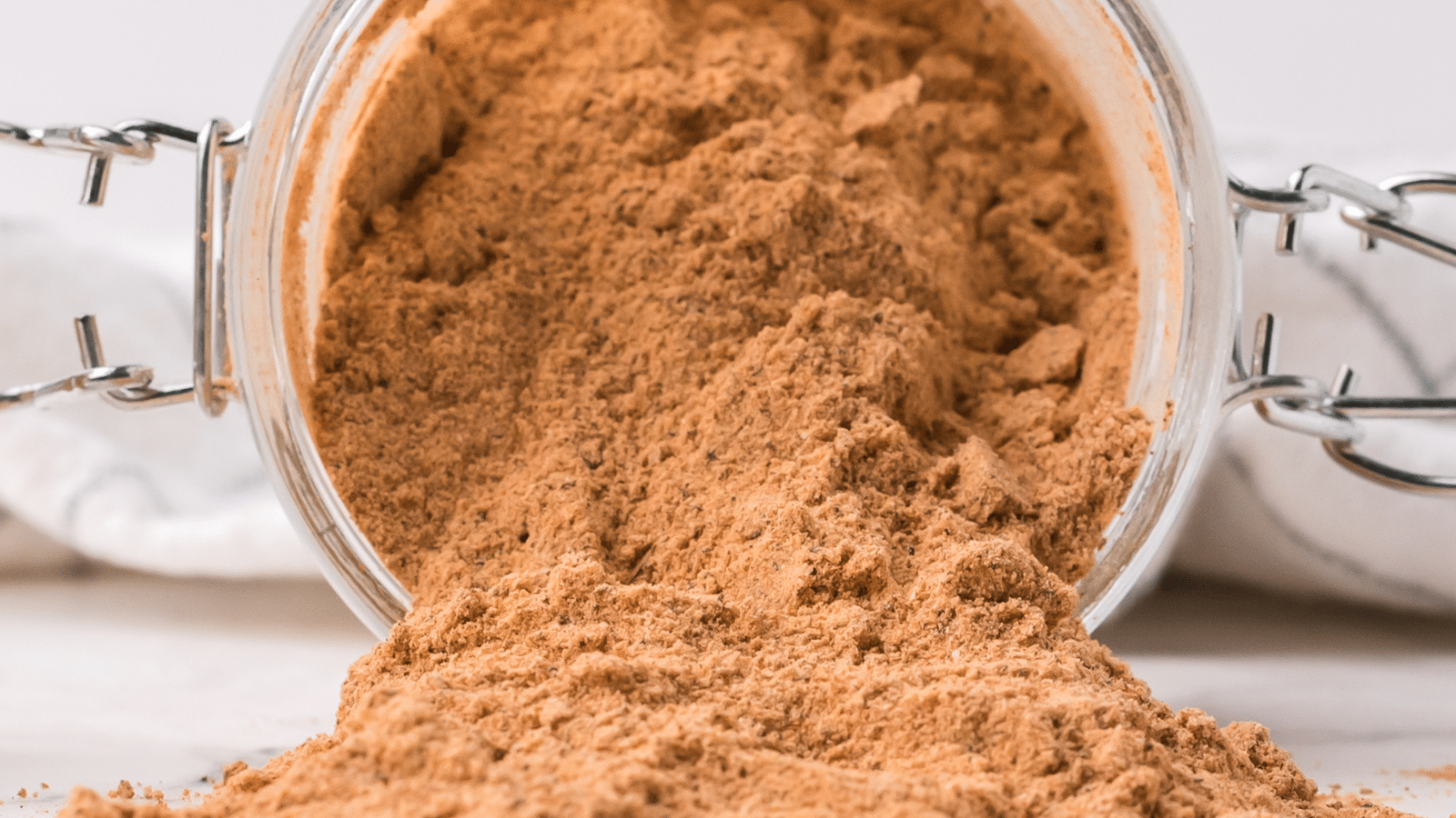 a close up of sweet and spicy homemade BBQ seasoning spilled out of a jar on the counter