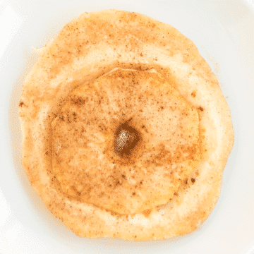 a close up of one apple ring pancake on a white plate