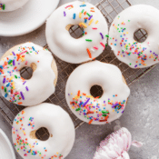 five baked vanilla donuts with vanilla glaze and multicolored sprinkles