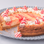 candy cane swirl cheesecake with one slice missing on a metal platter