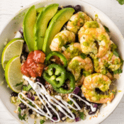 cilantro lime shrimp burrito bowl with rice and beans in a white bowl with sour cream