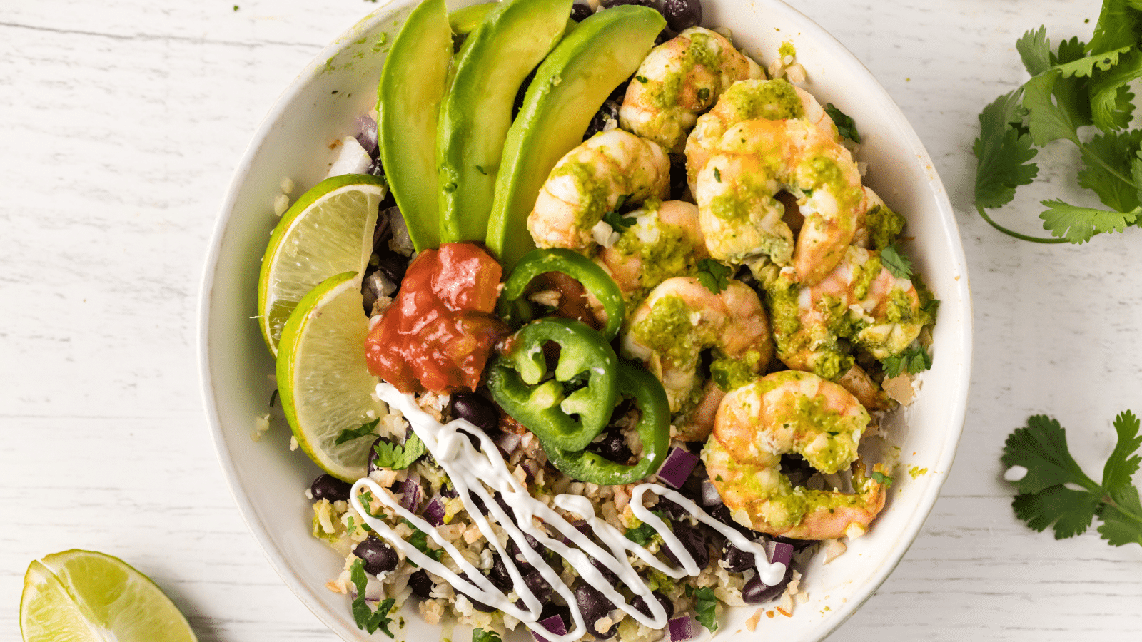 cilantro lime shrimp burrito bowl with rice and beans in a white bowl