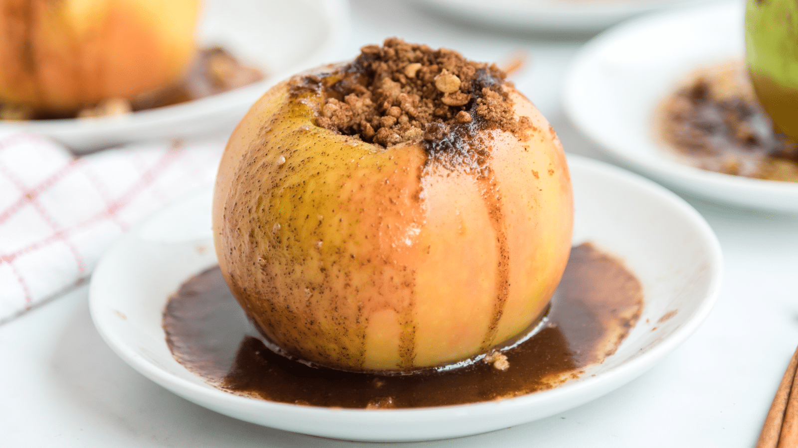 a close up of a brown sugar stuffed baked apple on top in a white dish with a spoon