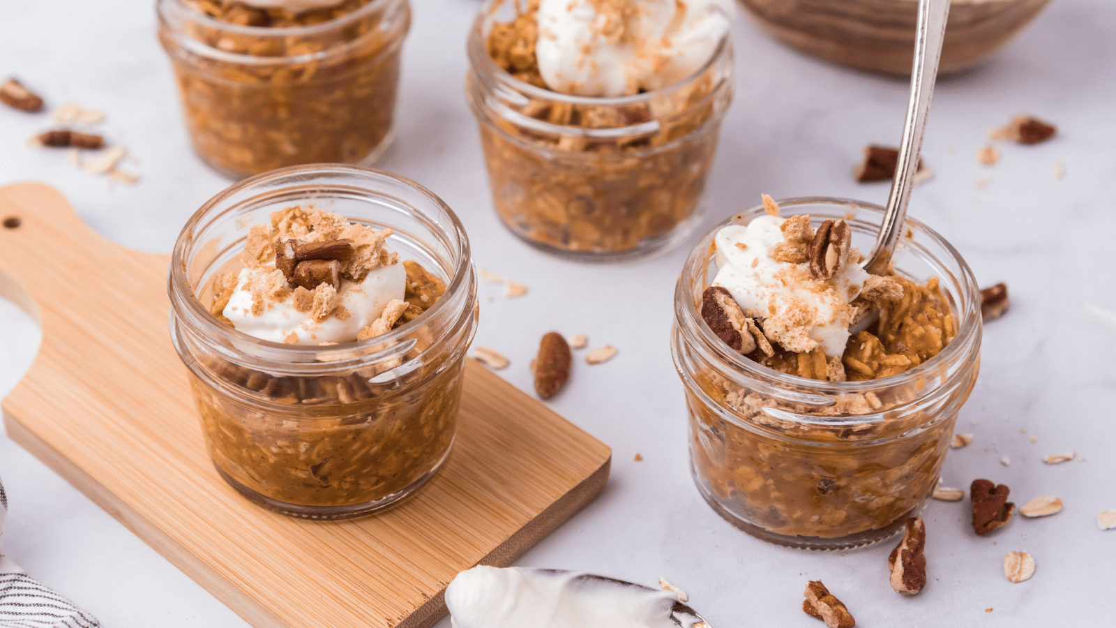 three jars of pumpkin pie overnight oats with whipped cream and pecans