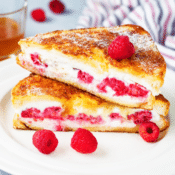 raspberry cheesecake stuffed french toast on a white plate with raspberries