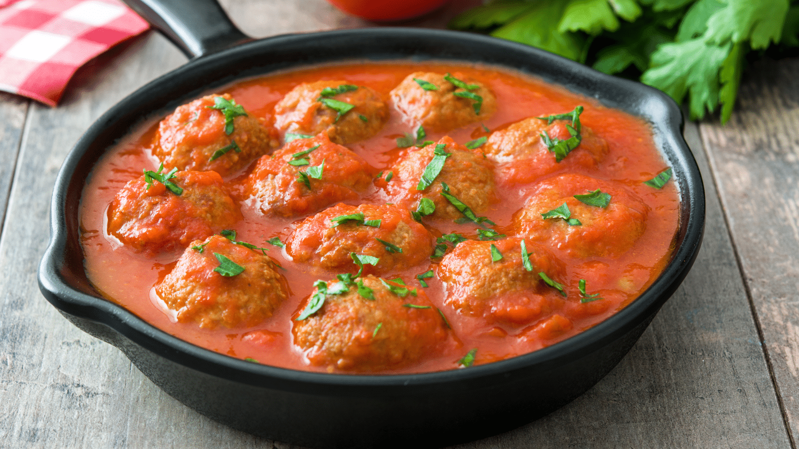 a cast iron skillet filled with homemade meatballs and marinara sauce