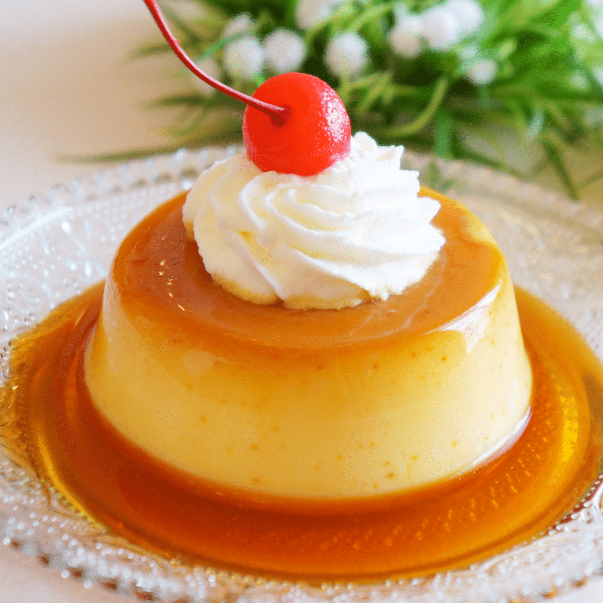 an individual serving of pumpkin flan topped with whipped cream and a cherry
