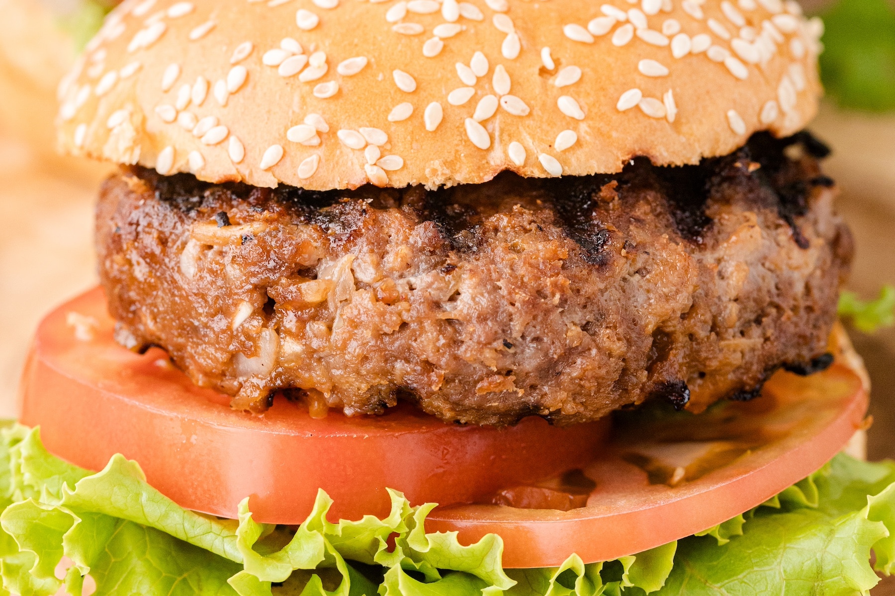 a close up of the best BBQ burger on a sesame seed bun with lettuce and tomato