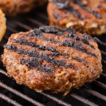 a close up of the best grilled BBQ burgers on the grill grates