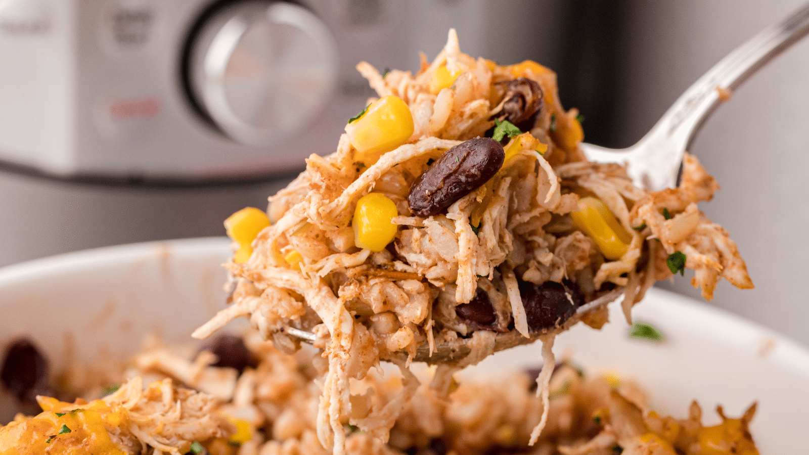 a big spoonful of cheesy chicken and rice with beans and corn in front of an Instant Pot