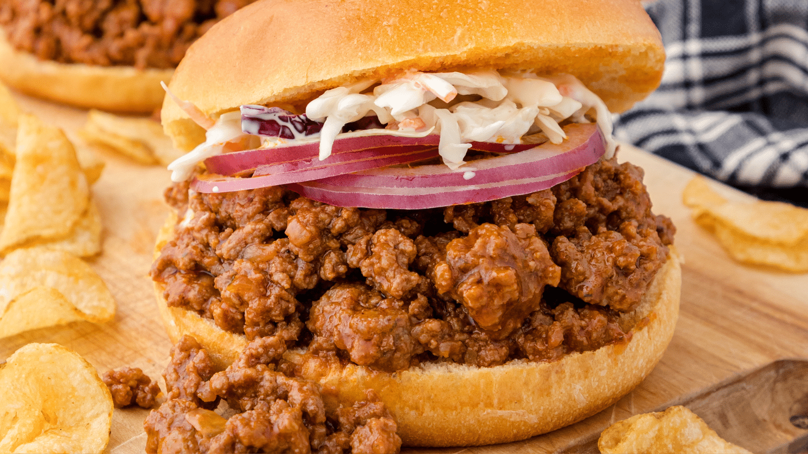 a close up of one Instant Pot sloppy joe sandwich with slices of red onion and coleslaw on top