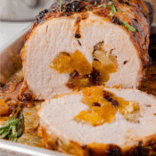 apricot stuffed pork loin with one slice missing, showing the stuffing which contains apricots and cranberries